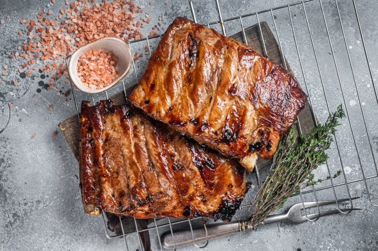 BBQ grilled pork ribs in Barbecue sauce on a grill. Gray background. Top view