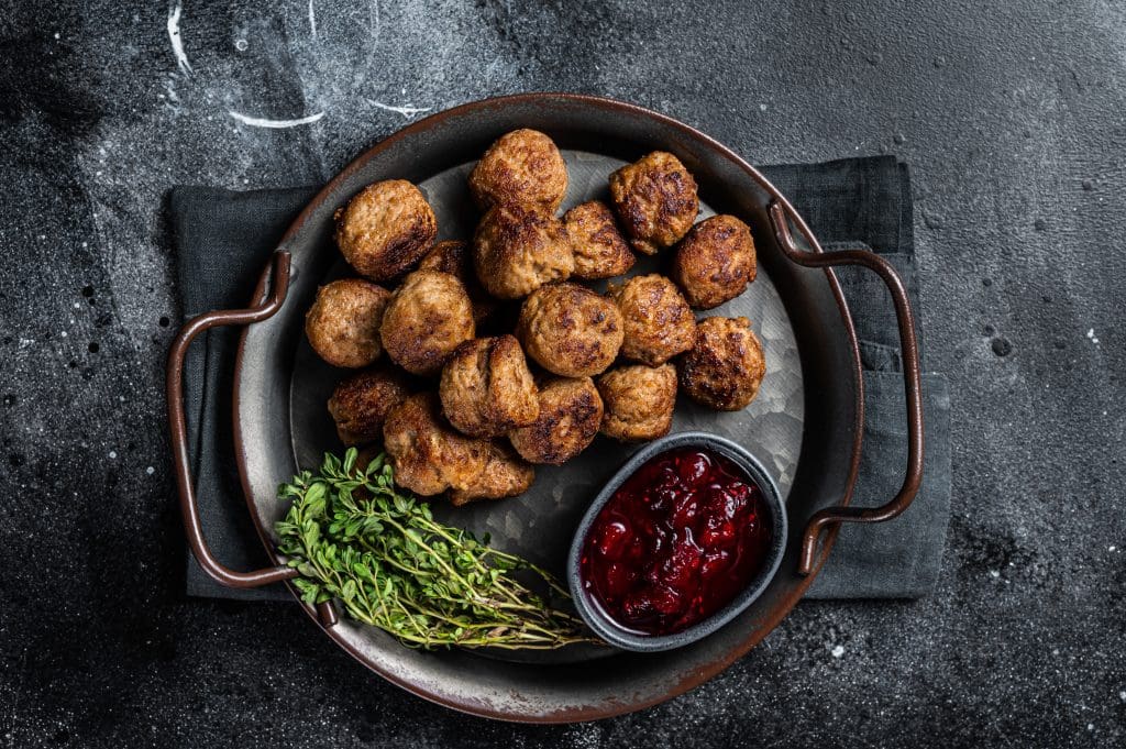 Homemade Swedish meatballs with lingonberries jam. Black background. Top view