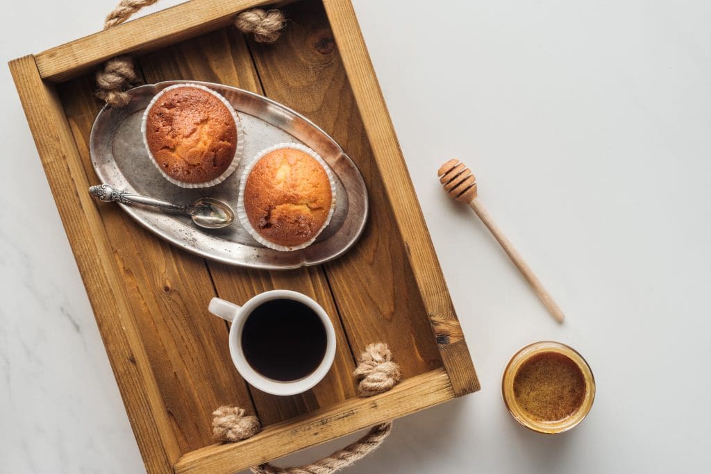 top view of cup of coffee with muffins on tray on white marble