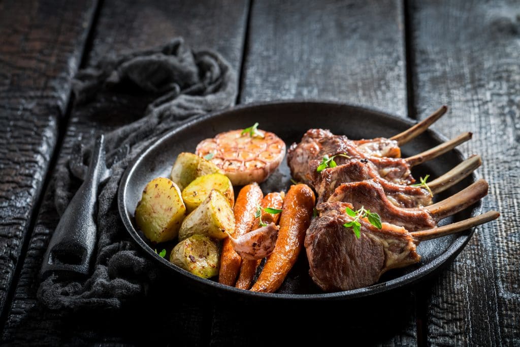 Closeup of roasted lamb ribs with thyme on dark background