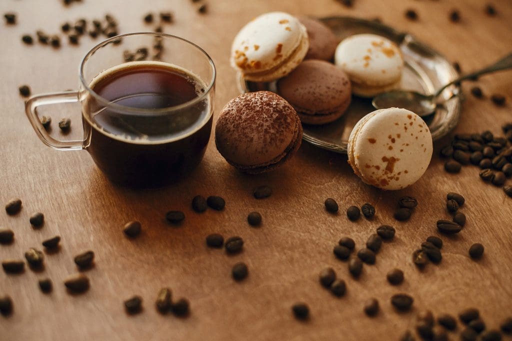 Coffee in glass cup and delicious macaron cookies on vintage plate