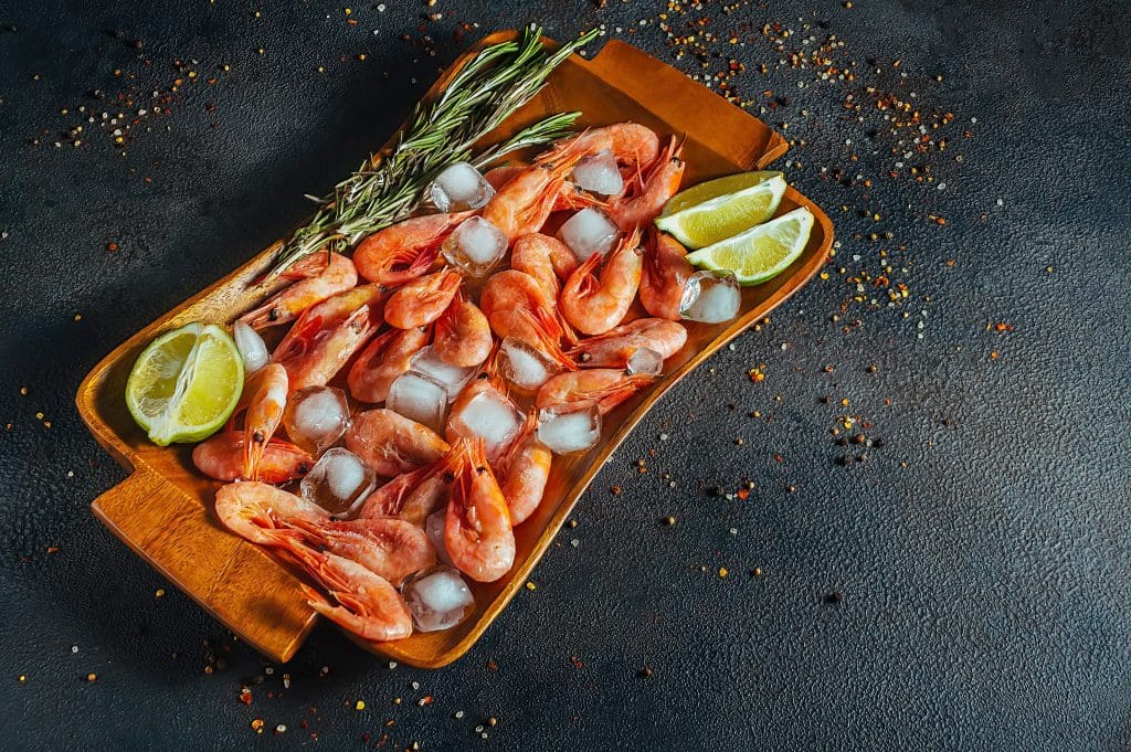 raw shrimp with ice and lemon on a platter