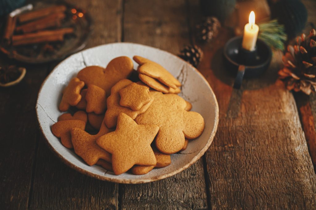 Freshly baked christmas gingerbread cookies in plate on background of rustic table with candle