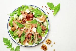 Grape salad with prosciutto, blue cheese, arugula, walnuts on white background
