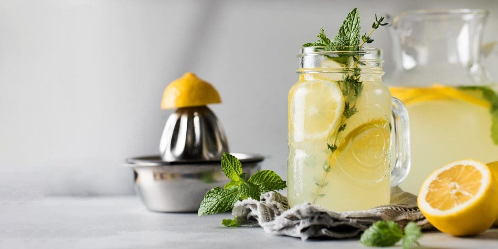 Lemonade with fresh lemon slices and mint leaves in a glass. A summer refreshing drink. Banner