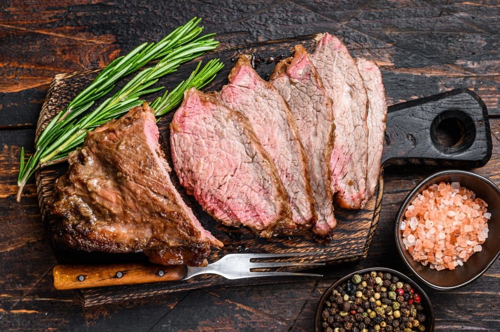 Sliced Roast beef sirloin tri tip steak bbq. Dark wooden background. Top view