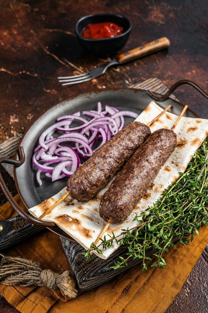 Turkish Adana Kebab from mince lamb beef meat on Skewer with flatbread and onion.