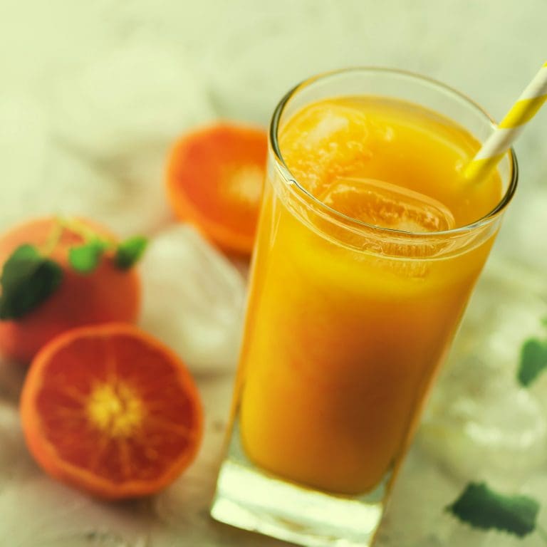Fresh orange juice, mint and ice on white background, top view, copy space. Summer cocktail, drink