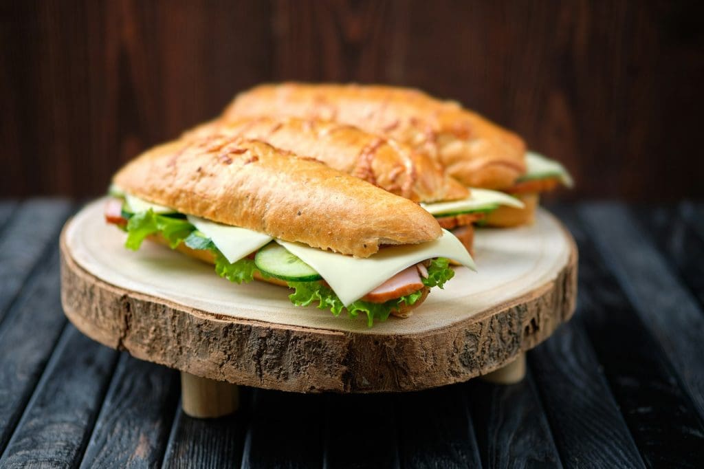 Hunter's sandwich with ham, cucumber, cheddar cheese on wooden board