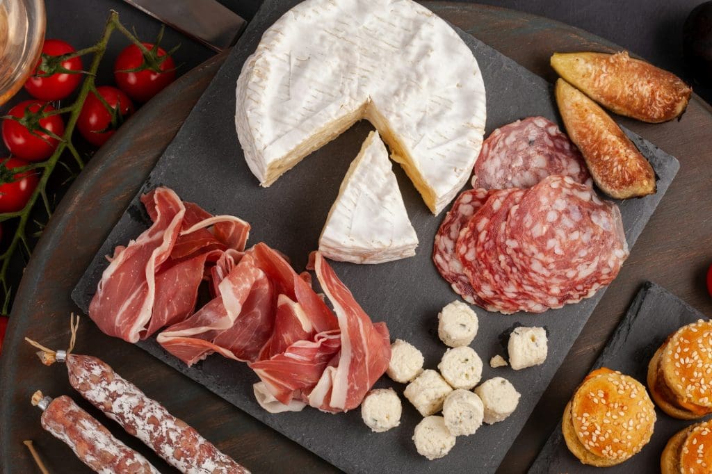 Appetizers table with differents antipasti, cheese, charcuterie, snacks and wine. Mini burgers