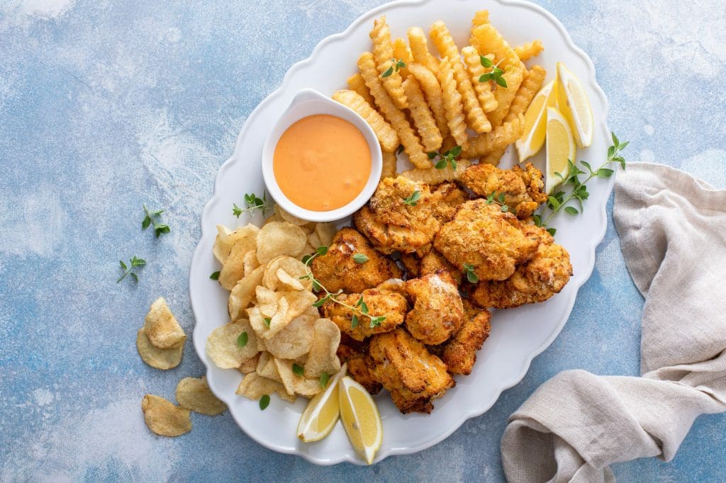 Fish and chips on a serving platter with dipping sauce