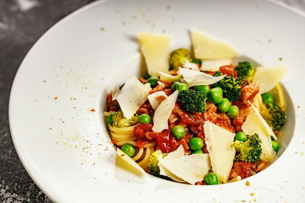 Close-up Appetizing pasta with meat in tomato sauce, vegetables and Parmesan cheese