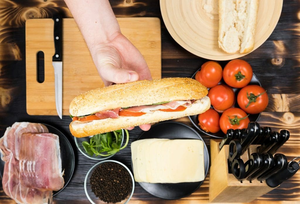 Hand holds a sandwitch over the kitchen table