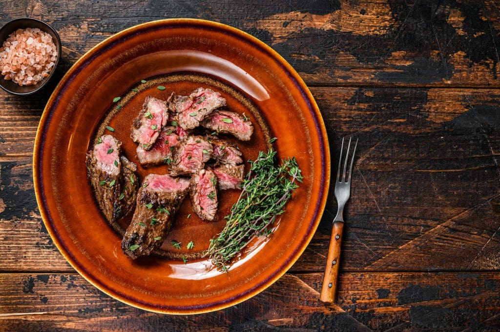 Sliced Grilled barbecue brisket steaks slices on a rustic plate. Dark wooden background.