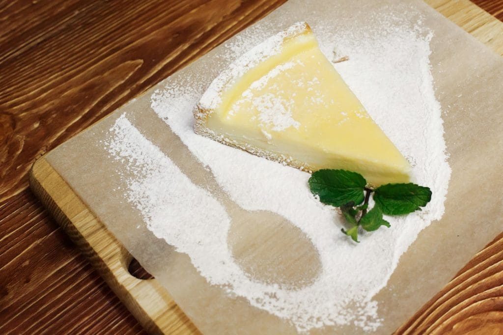 Delicious cheesecake with powder and mint serving on wooden desk