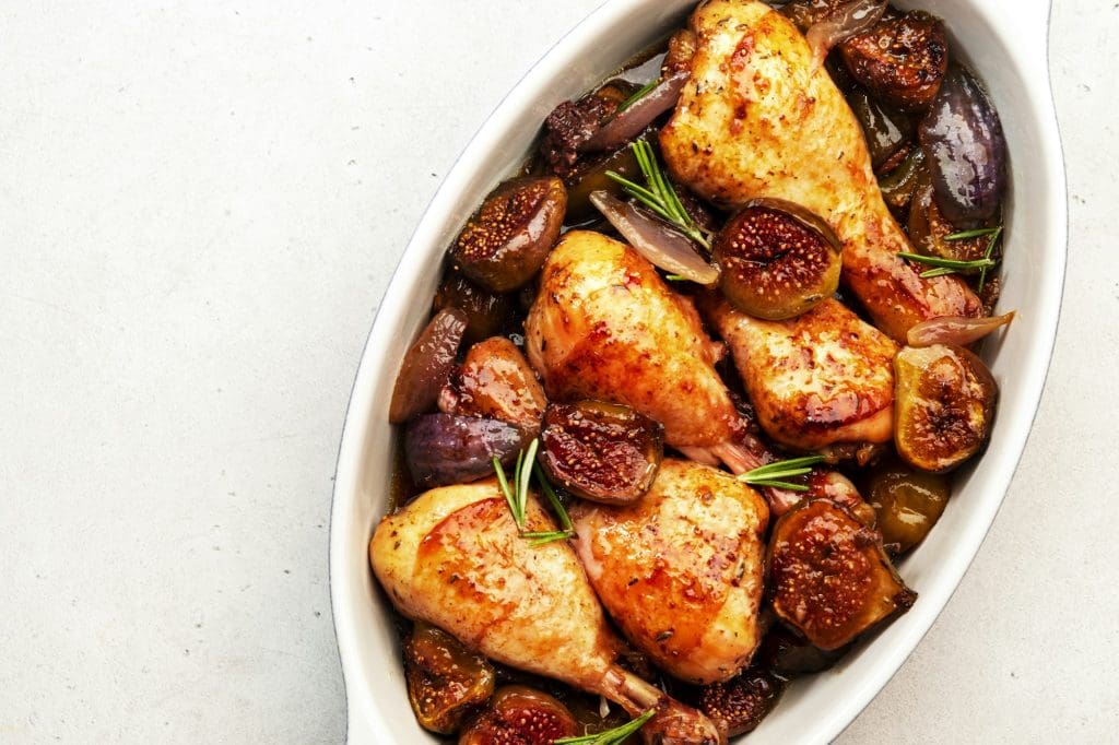 Baked chicken legs, drumsticks with figs and red onions in balsamic marinade in ceramic baking dish