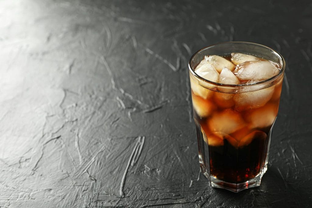 Glass of cold cola on black cement background